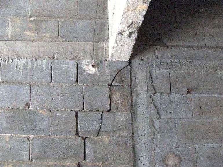 Parpaings fissurés sous le chaînage utilisé comme linteau, dans l’atelier