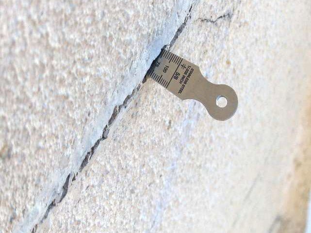 Fissure de façade dont l’ouverture est mesurée avec une jauge de fissure